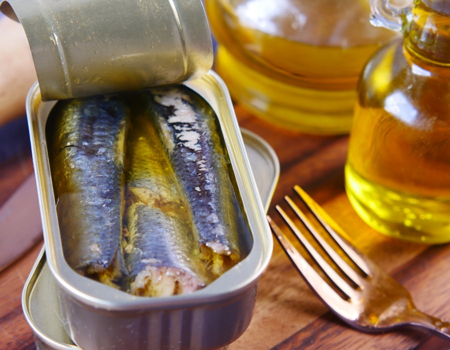 An open tin of sardines packed in oil beside a bottle of olive oil